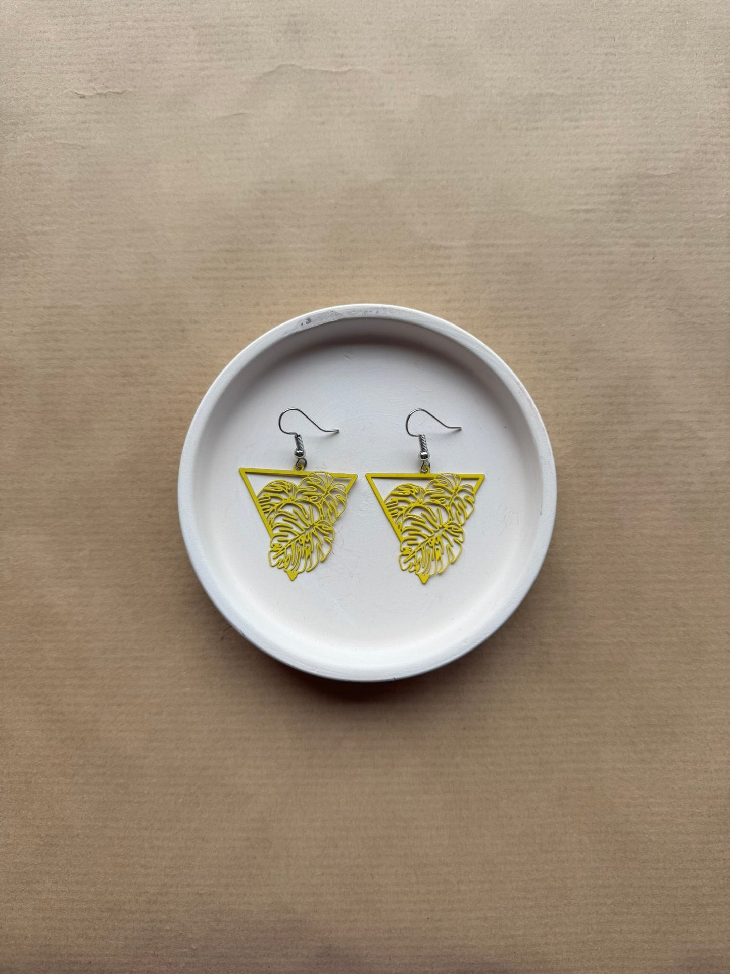 White dish with yellow earrings on a beige background