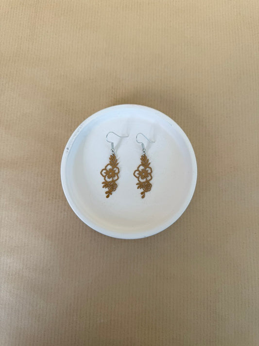 Camel earrings on a white circular stand against a beige background