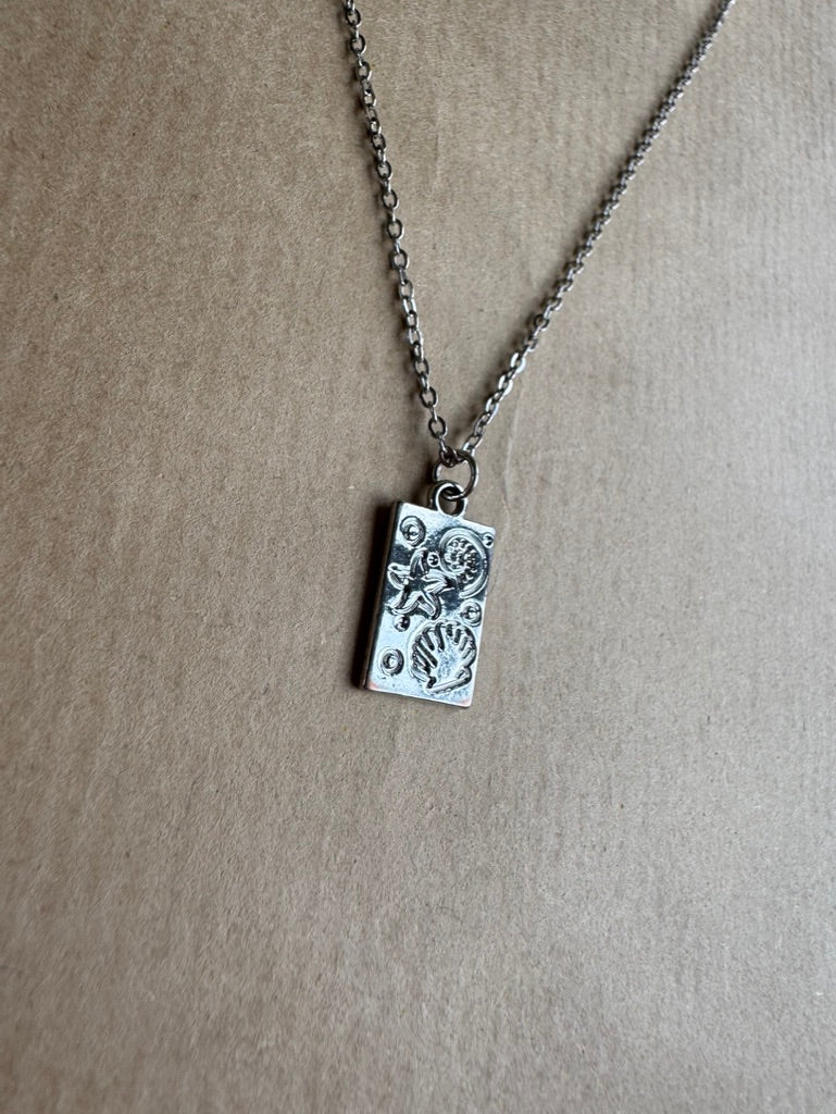 Silver necklace with a rectangular pendant on a beige background
