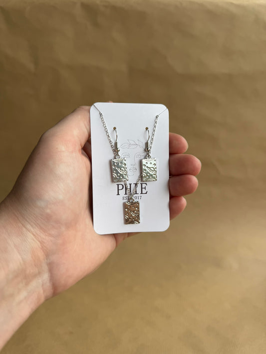 Hand holding a jewelry set on a beige background