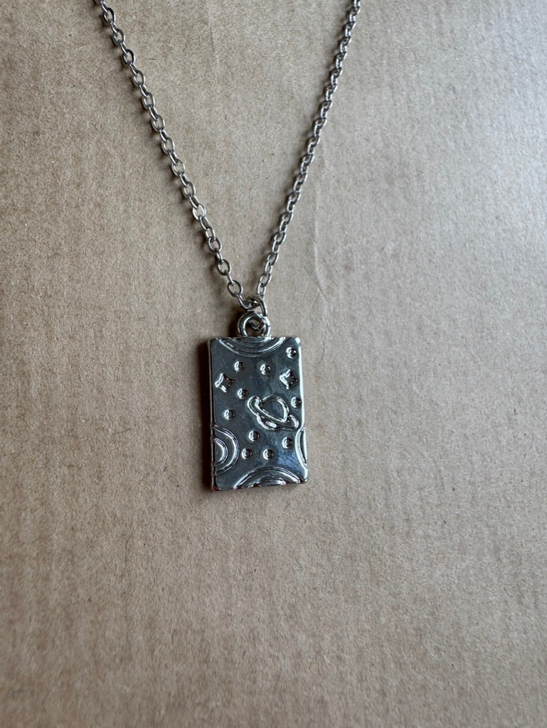 Silver necklace with a rectangular pendant on a beige background
