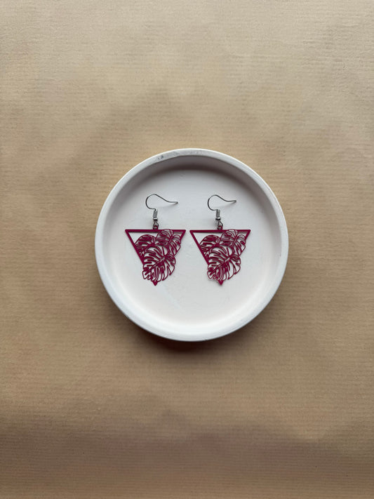 Pair of pink earrings on a white dish with a beige background