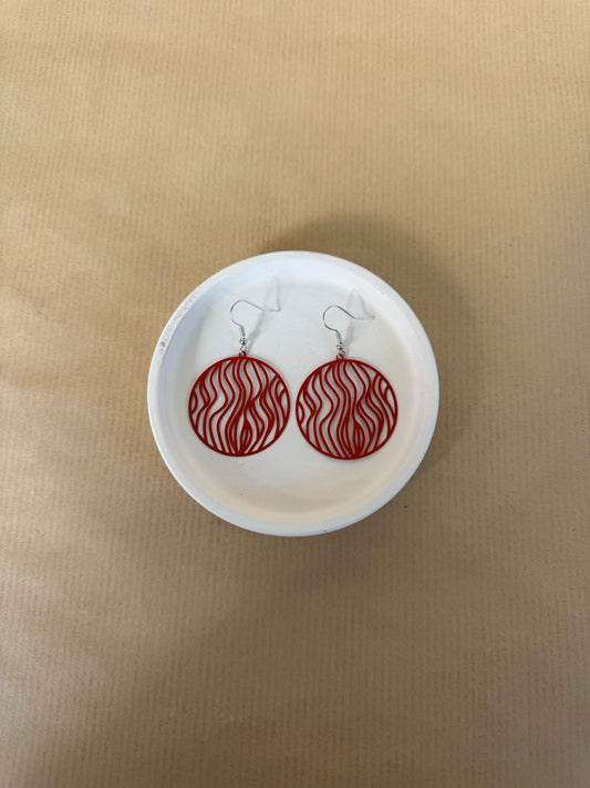 Red circular earrings on a white dish against a beige background