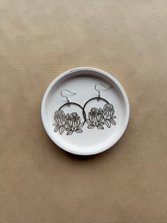 White dish with floral earrings on a beige background
