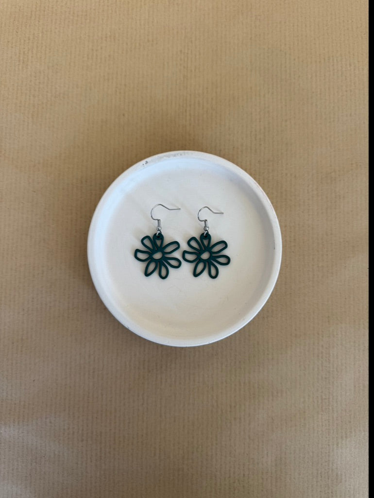 Forest Green Flower-shaped earrings on a white dish with a beige background