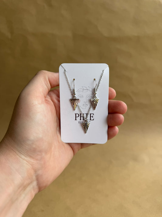 Hand holding a necklace on a branded card against a beige background