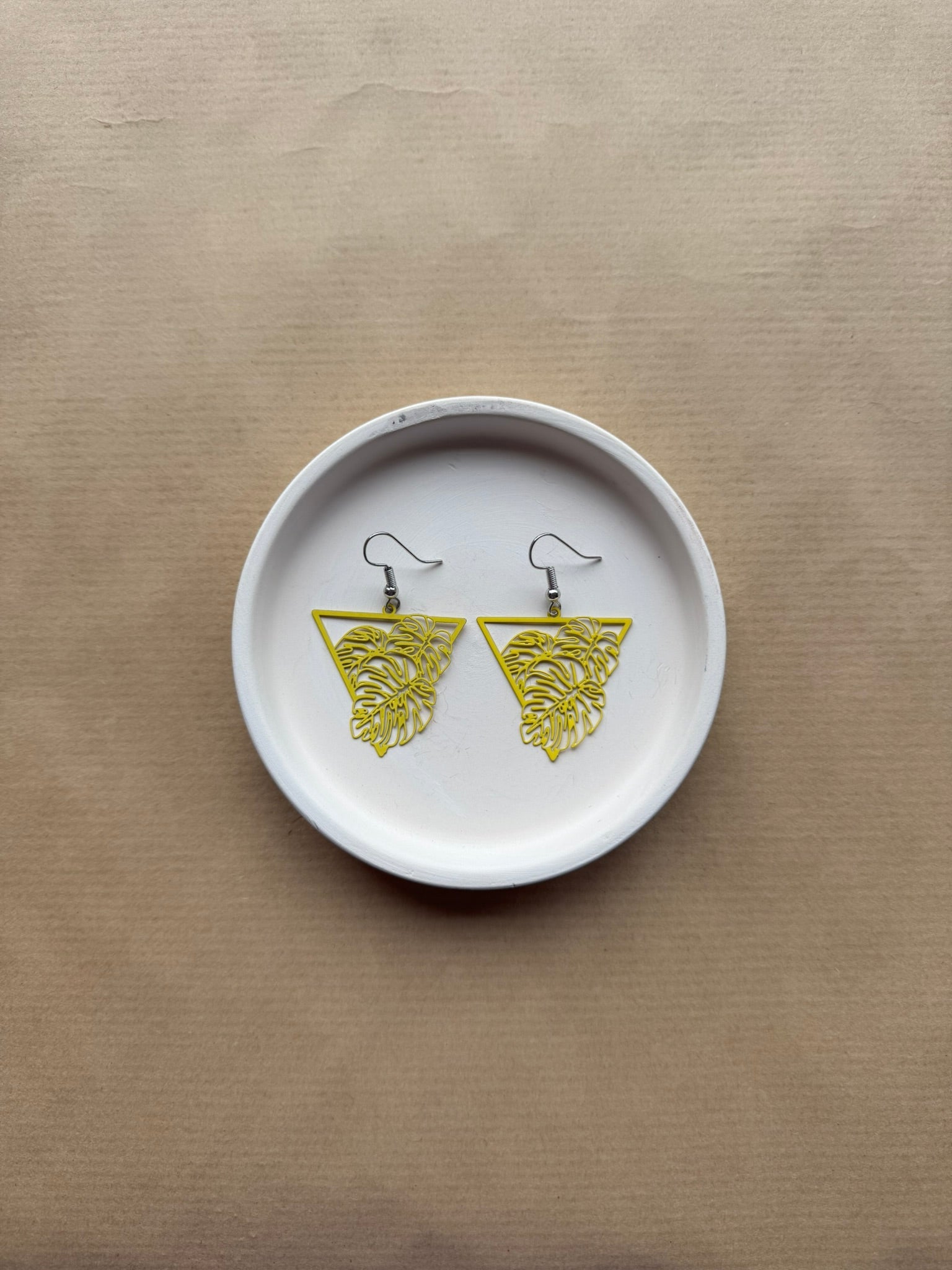 White dish with yellow earrings on a beige background