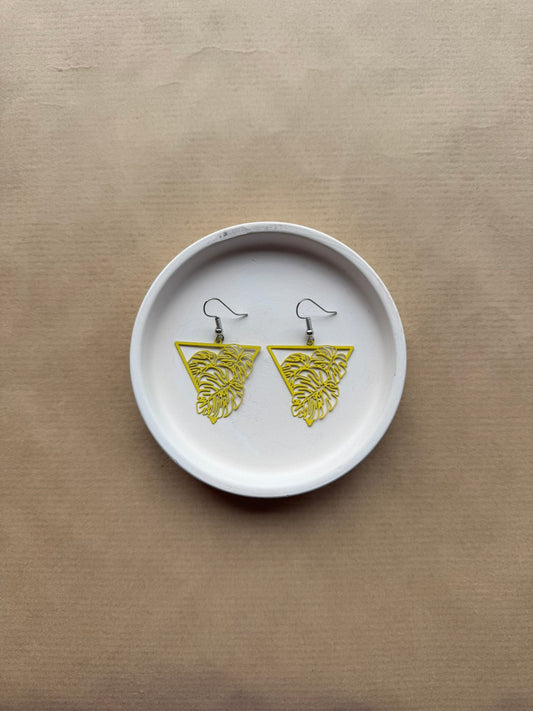 White dish with yellow earrings on a beige background