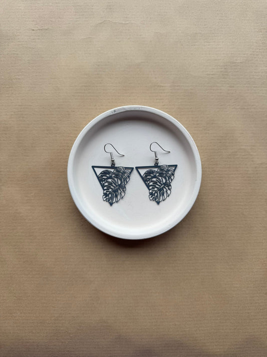 cobalt blue earrings on White ceramic dish on a beige background
