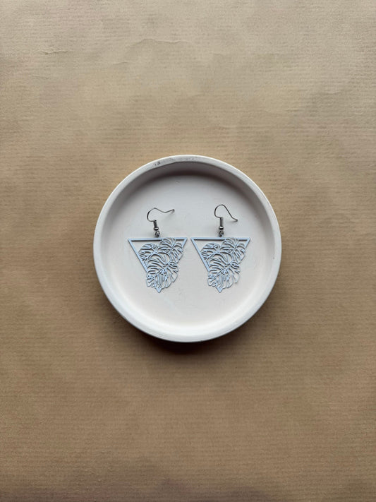 white earrings on white dish on brown background